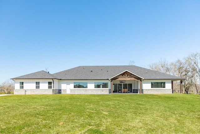 rear view of property featuring a lawn, roof with shingles, and a patio area