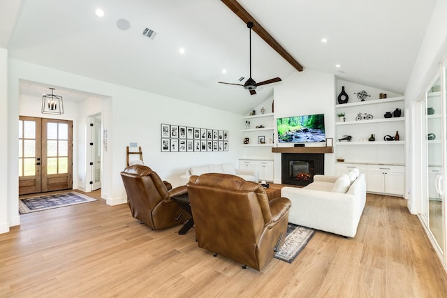 living room with visible vents, lofted ceiling with beams, french doors, a glass covered fireplace, and light wood-type flooring