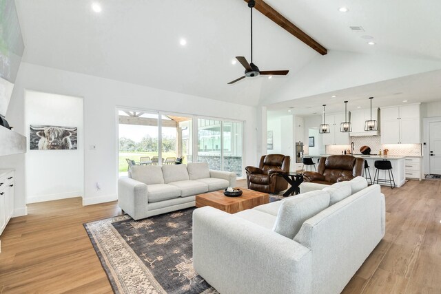 living room featuring visible vents, beam ceiling, high vaulted ceiling, and light wood-style flooring