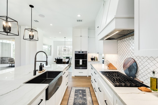 kitchen with visible vents, a sink, black gas cooktop, double oven, and custom exhaust hood