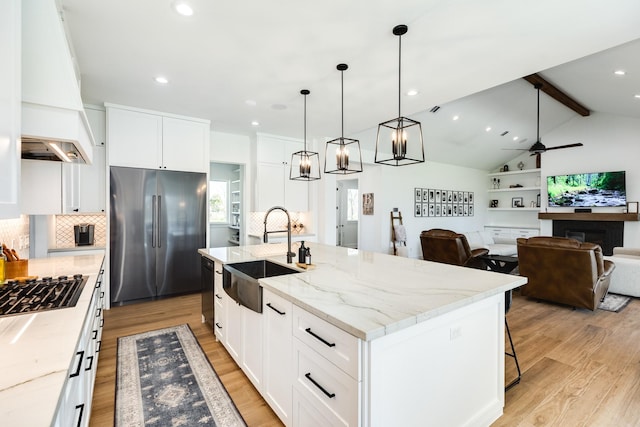 kitchen with light wood-type flooring, custom range hood, a sink, high quality fridge, and vaulted ceiling with beams