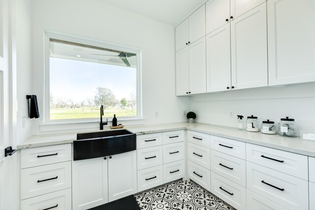 kitchen with white cabinetry, light stone countertops, and a sink