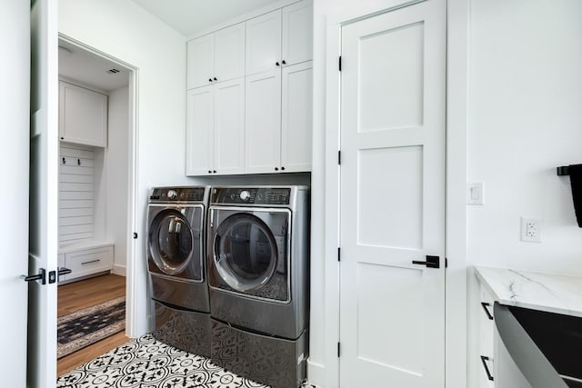 laundry area featuring cabinet space, light wood-style flooring, and washer and clothes dryer