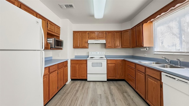 kitchen with light wood finished floors, visible vents, under cabinet range hood, white appliances, and a sink