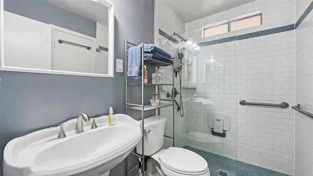 full bath with a sink, toilet, and a tile shower