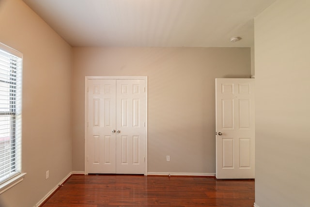 unfurnished bedroom featuring a closet, baseboards, and wood finished floors