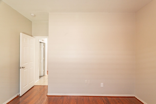 spare room featuring baseboards and wood finished floors