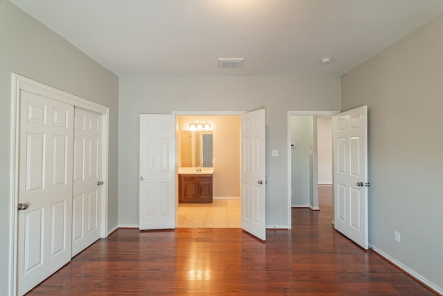 unfurnished bedroom featuring a closet, visible vents, dark wood-type flooring, and baseboards