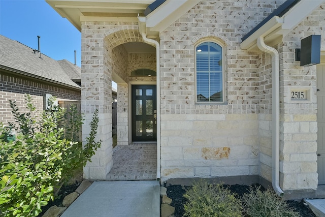 property entrance featuring french doors, brick siding, and a shingled roof