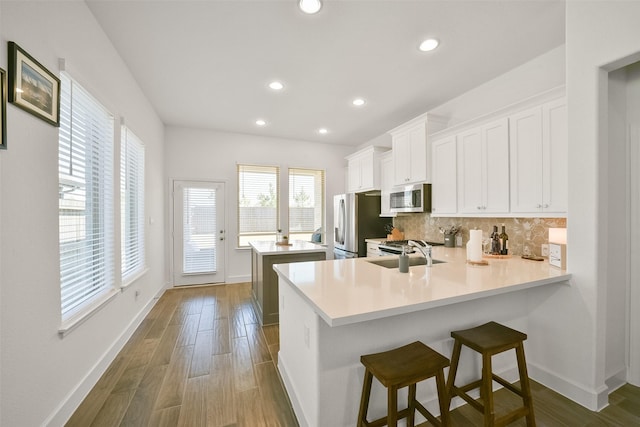 kitchen featuring backsplash, a center island, light countertops, stainless steel appliances, and a sink