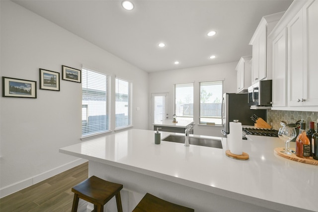 kitchen with stainless steel microwave, a peninsula, light countertops, and a sink