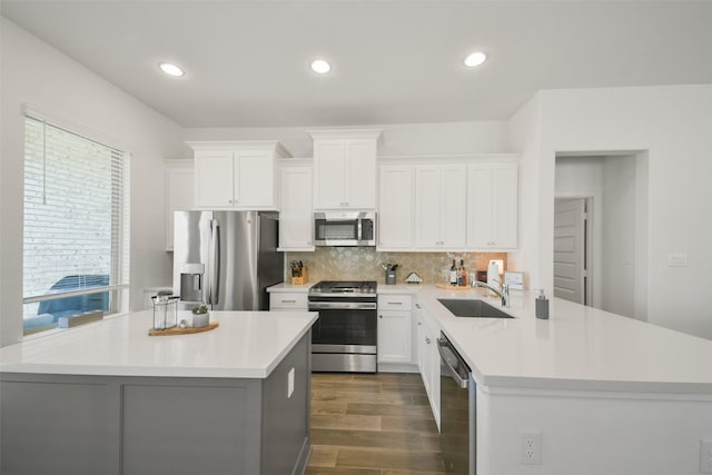 kitchen with dark wood-type flooring, light countertops, decorative backsplash, stainless steel appliances, and a sink