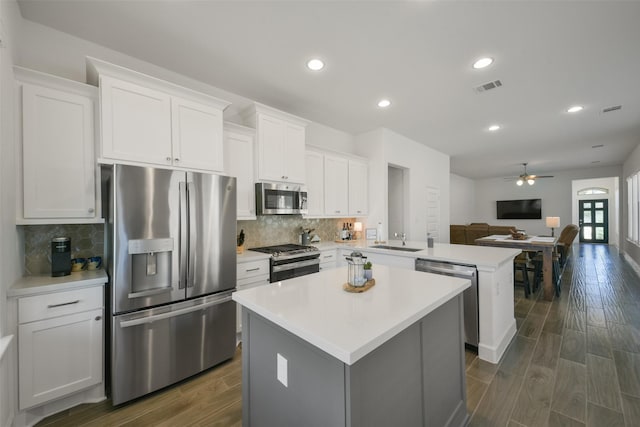 kitchen with a kitchen island, a peninsula, a sink, appliances with stainless steel finishes, and open floor plan