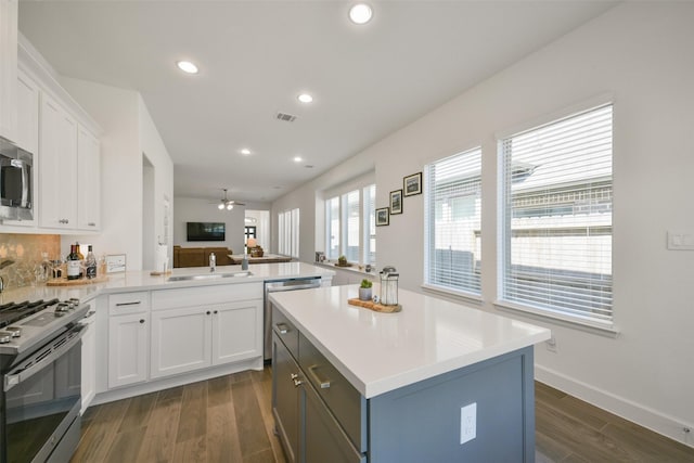 kitchen featuring visible vents, open floor plan, gas range, a peninsula, and a sink