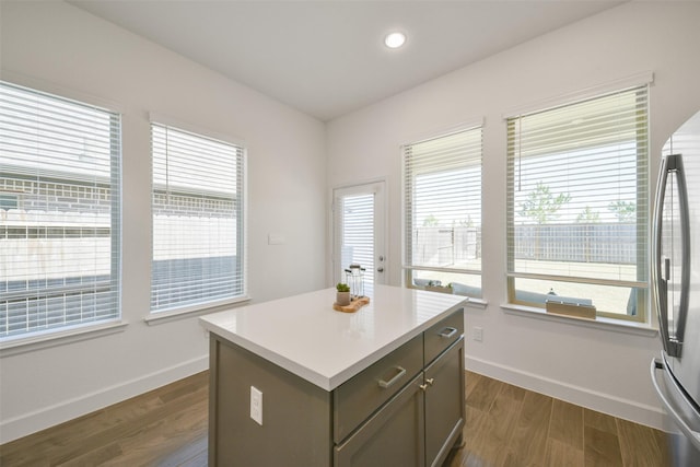 kitchen with a kitchen island, freestanding refrigerator, baseboards, and dark wood-style flooring