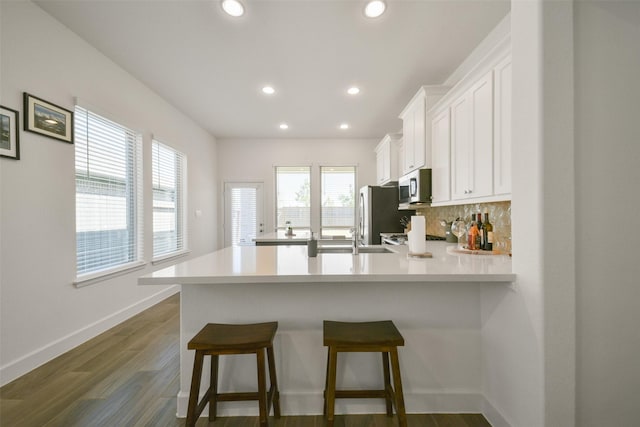 kitchen featuring backsplash, appliances with stainless steel finishes, white cabinetry, and light countertops