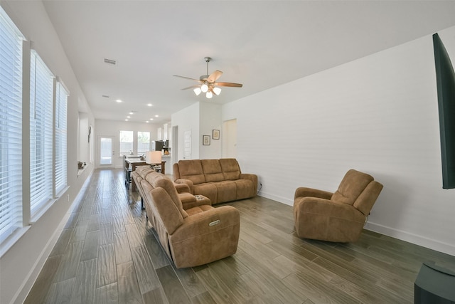 living room featuring visible vents, ceiling fan, baseboards, and wood finished floors