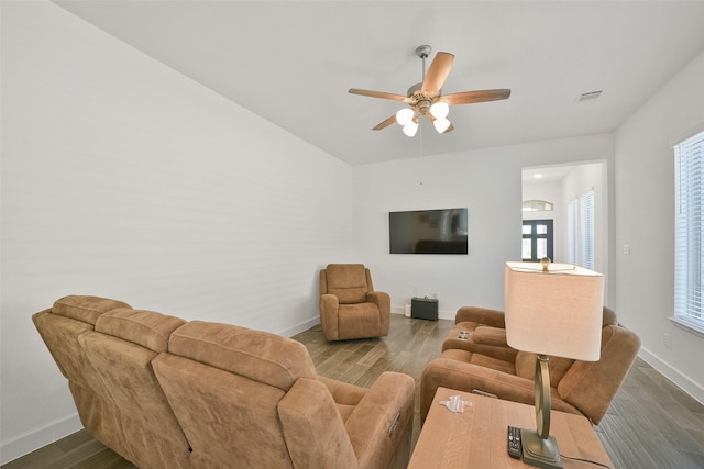 living area featuring ceiling fan, visible vents, baseboards, and wood finished floors