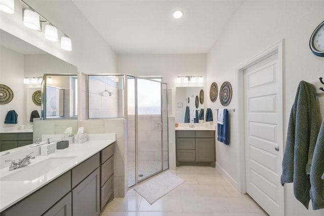 full bath featuring a shower stall, two vanities, tile patterned floors, and a sink