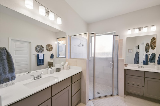 bathroom featuring two vanities, a stall shower, and a sink