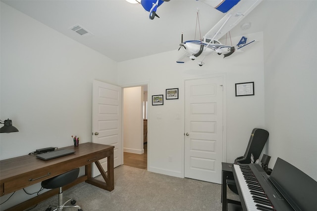 office space with baseboards, visible vents, and light carpet