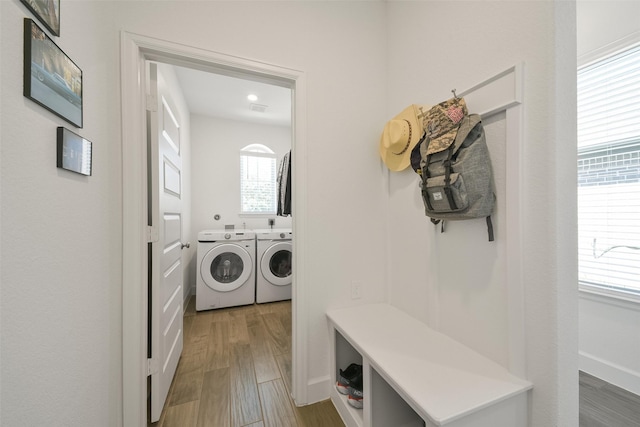 clothes washing area with laundry area, wood finished floors, visible vents, and washer and clothes dryer