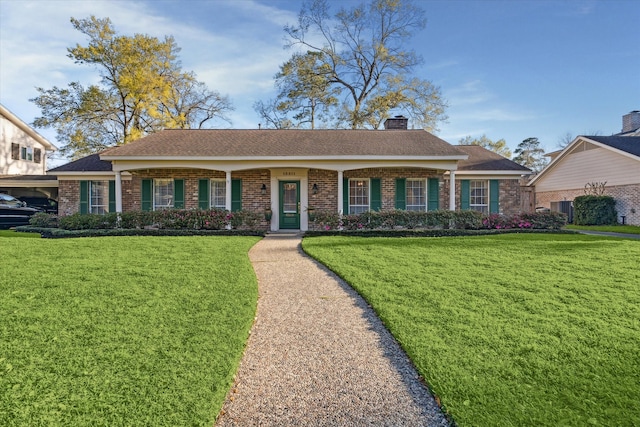 view of front of property with brick siding, a chimney, and a front yard