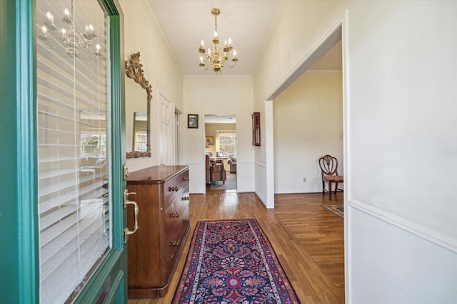 foyer entrance with an inviting chandelier, wood finished floors, and ornamental molding