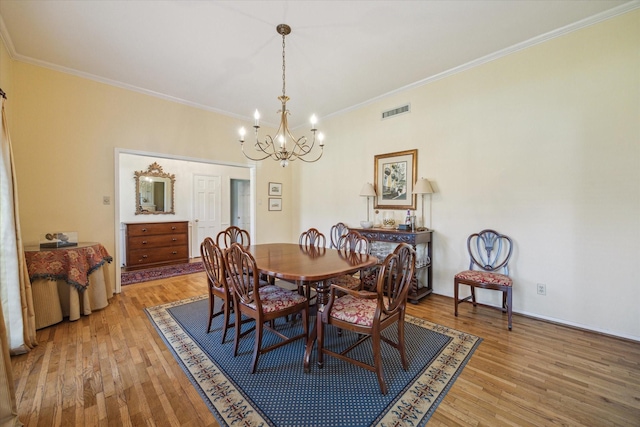 dining space featuring visible vents, a chandelier, ornamental molding, and light wood finished floors