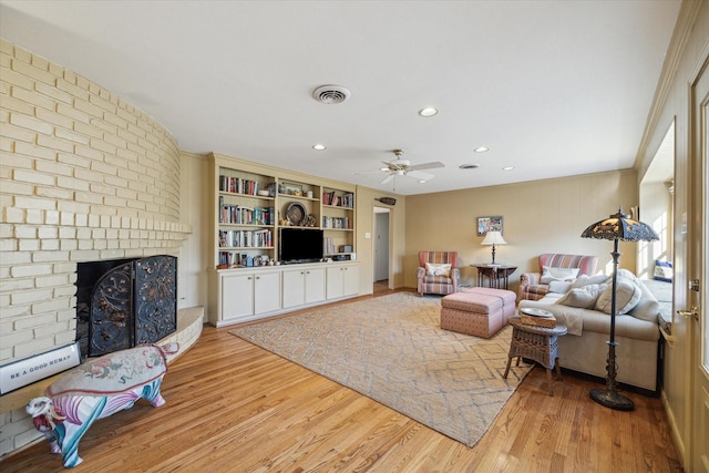 living area with visible vents, wood finished floors, recessed lighting, a brick fireplace, and ceiling fan