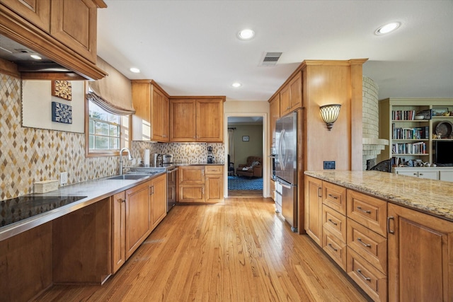 kitchen with light wood finished floors, visible vents, light stone counters, freestanding refrigerator, and a sink