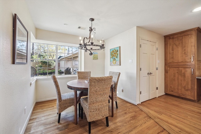 dining area featuring visible vents, light wood-style floors, baseboards, and a chandelier