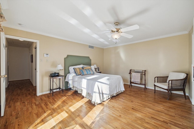 bedroom with visible vents, light wood-style flooring, crown molding, baseboards, and attic access