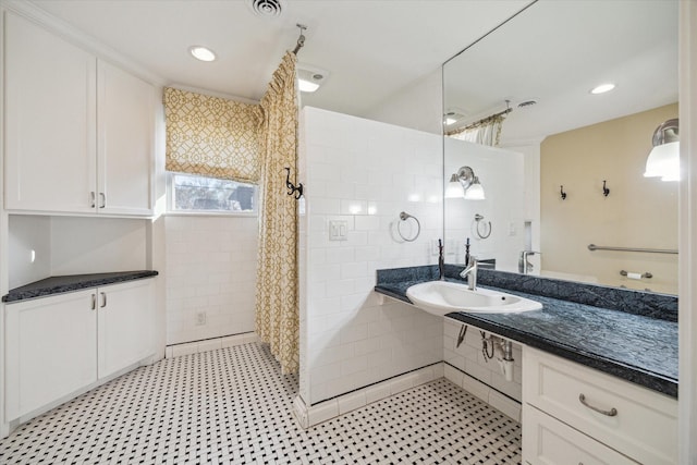 bathroom featuring a tile shower, visible vents, recessed lighting, and a sink