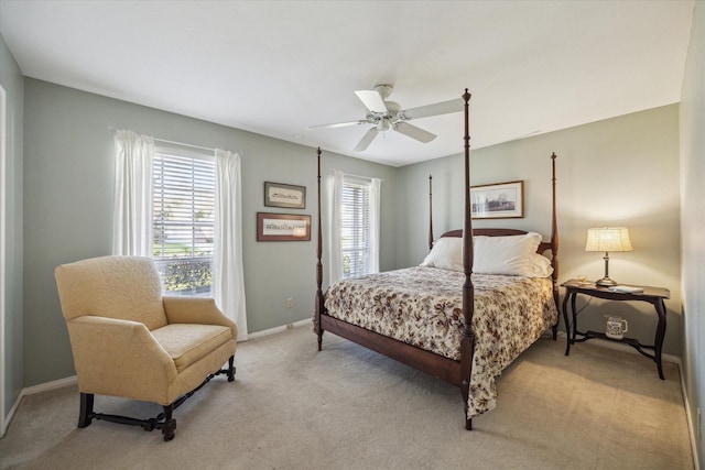 bedroom featuring baseboards, multiple windows, light colored carpet, and a ceiling fan