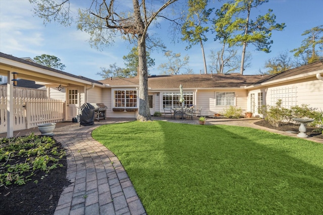 rear view of house with fence, a lawn, and a patio area