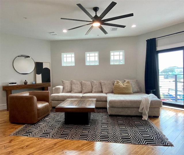 living room with a wealth of natural light, visible vents, recessed lighting, and wood-type flooring