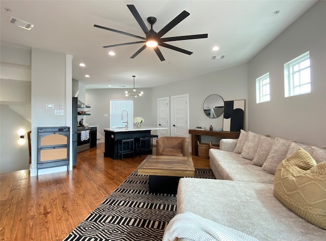 living area featuring visible vents, recessed lighting, ceiling fan with notable chandelier, and wood finished floors