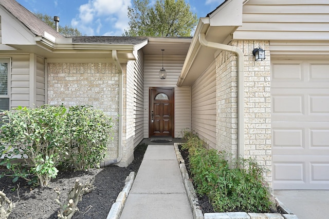 view of exterior entry with brick siding and an attached garage