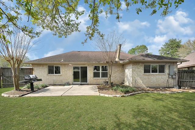 rear view of property with brick siding, a yard, a patio area, and fence