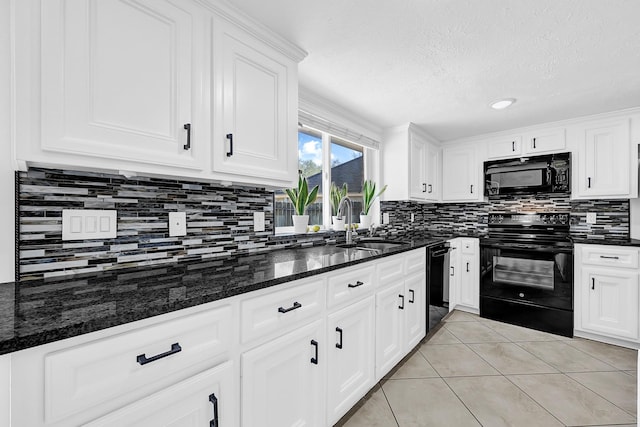 kitchen featuring dark stone counters, light tile patterned flooring, white cabinets, black appliances, and a sink