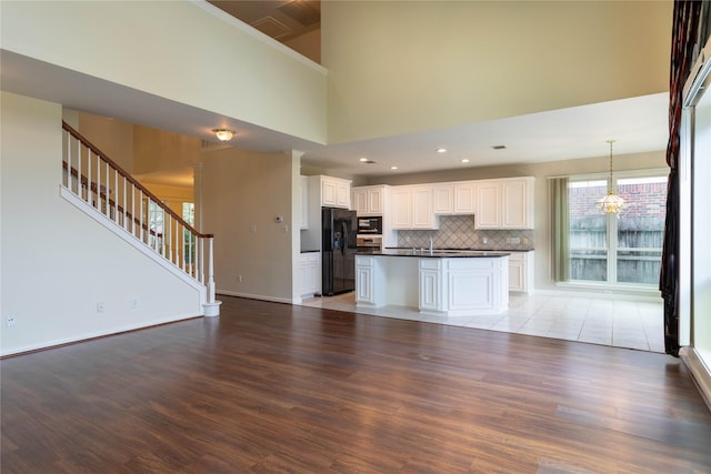 kitchen with dark countertops, wood finished floors, open floor plan, built in microwave, and black refrigerator with ice dispenser