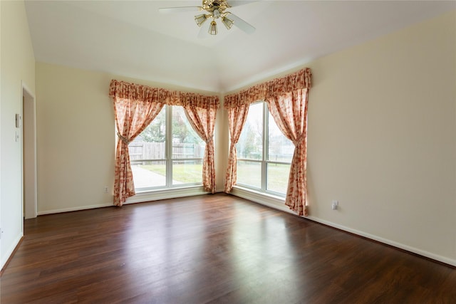 spare room featuring baseboards, dark wood finished floors, and a ceiling fan