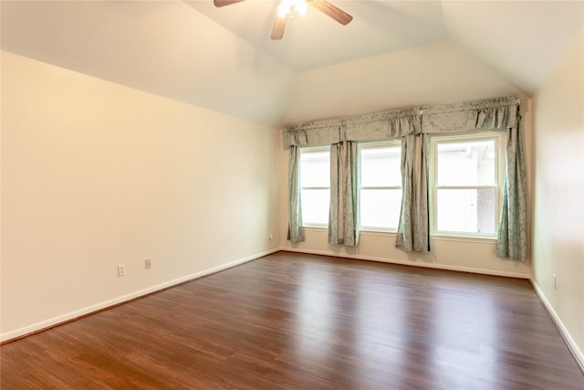 spare room featuring baseboards, a ceiling fan, dark wood-style flooring, and vaulted ceiling