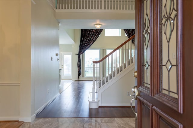 entryway with baseboards, stairs, and a towering ceiling