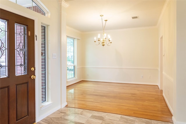 foyer entrance featuring light wood finished floors, visible vents, baseboards, ornamental molding, and a notable chandelier