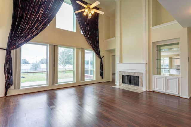 unfurnished living room with a tiled fireplace, high vaulted ceiling, a ceiling fan, and wood finished floors