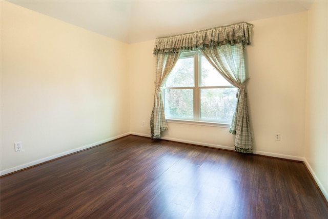 empty room featuring baseboards and dark wood-type flooring