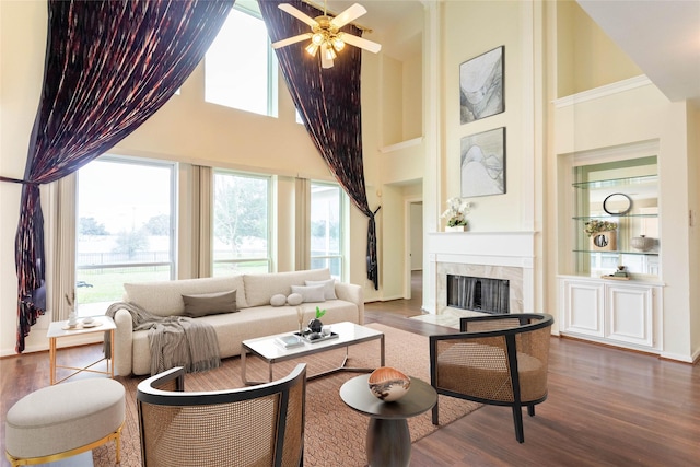 living room featuring a ceiling fan, wood finished floors, a high end fireplace, and high vaulted ceiling