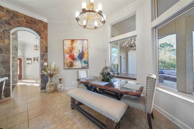 dining room featuring light tile patterned floors, baseboards, arched walkways, crown molding, and a chandelier